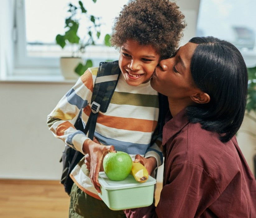 Kid with healthy lunch and a kiss on the cheek from mom